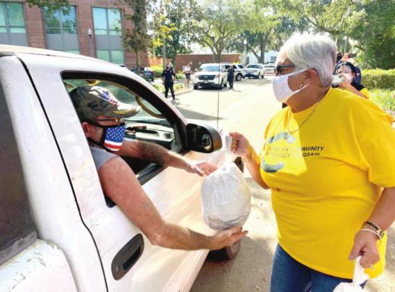 Kissimmee Mayor Olga Gonzalez hands a turkey to a meal recipient. NEWS-GAZETTE PHOTO/BRIAN MCBRIDE