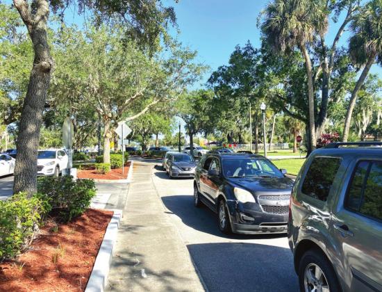 A line of vehicles wait behind Kissimmee City Hall to get Thanksgiving meals. NEWS-GAZETTE PHOTO/BRIAN MCBRIDE