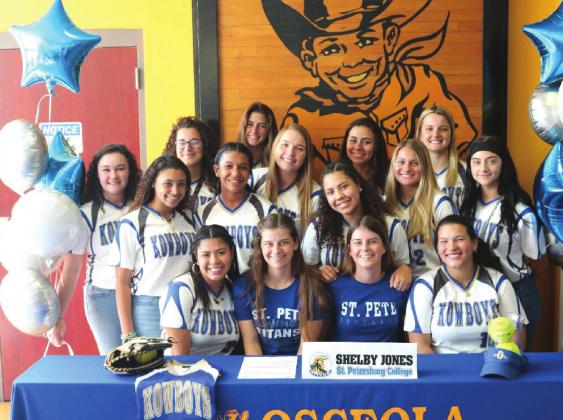 Surrounded by her teammates, Shelby Jones (front row third from right) signs her letter of intent to play softball at St. Petersburg College. PHOTO/AMANDA WATFORD