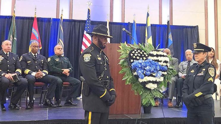 Police officers from St. Cloud and Kissimmee stand watch over a memorial wreath after blue roses were added by colleagues and families to honor Osceola County’s fallen law enforcement officers at Tuesday’s annual memorial service. (Photos/Ken Jackson).