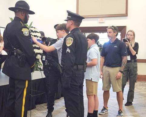 Members of the families of the fallen law enforcement heroes place a blue rose on a memorial wreath at Tuesday's service. (Photos/Ken Jackson)