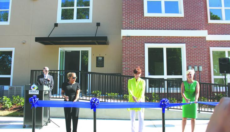 From left, Kissimmee Vice Mayor Olga Castano, Jim Shanks’ widow Elaine and County Commissioner Cheryl Grieb cut the ceremonial ribbon for Dillingham Apartments Tuesday. RIGHT - A plaque dedicating it to Jim Shanks adorns the building. PHOTO/KEN JACKSON
