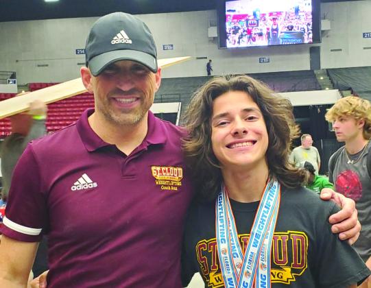 St. Cloud sophomore Michael Ziss proudly displays his two gold medals from the state weightlifting championships in Lakeland on Saturday. He is pictured with Coach Cory Aun, whose Bulldog team finished in third place. PHOTO/ST. CLOUD HIGH SCHOOL