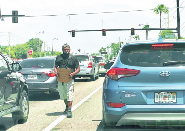 A panhandler walks between traffic at the intersection of U.S. Highway 192 and Bass Road in Kissimmee. NEWS-GAZETTE PHOTO/BRIAN MCBRIDE