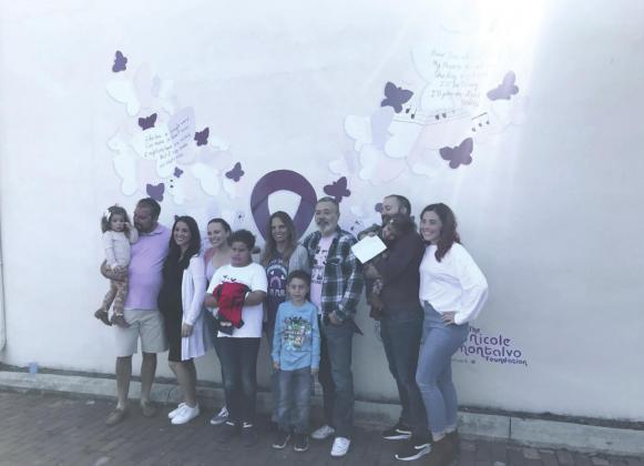 Nicole Montalvo’s family helped dedicate a new Help Now domestic violence mural in downtown Kissimmee Saturday: parents Ed and Elaine, siblings Edward, Steven and Christina, son Elijah, sisters-in-law Brittany and Celestine and nieces and nephews Eddie, Deliliah and Vivi. Note the accompanying sunbeam. SUBMITTED PHOTO