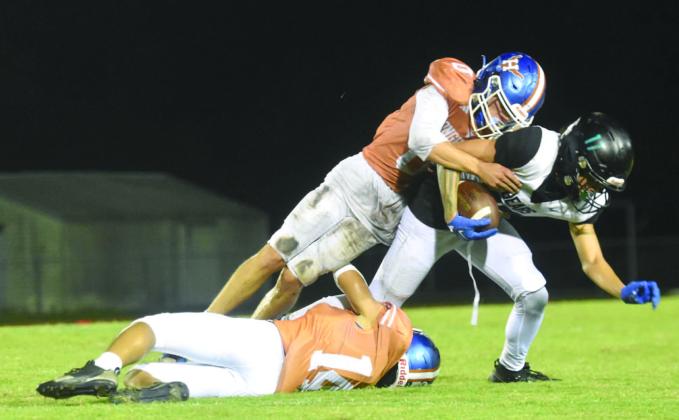 Harmony defenders Chase Adams (0) and Jaylen Carr (14) team up to take down Bayside’s Jaylen Miranda in the Longhorns’ 17-7 Friday. Harmony heads to Lake Howell this week to go for the winning streak. PHOTO/KATIE WILLIAMS