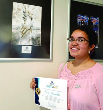 Graduating Tohopekaliga High senior Sara Jaramillo shows off her artwork now part of the N.E.S.T. Gallery on the second floor of the Osceola County Courthouse. PHOTO/KEN JACKSON