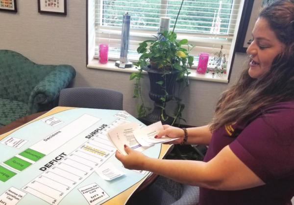 County Commissioner Peggy Choudhry shows off a board game, played by students that make them keep a balanced budget despite challenges, at a recent Osceola County Student Committee meeting. PHOTO/KEN JACKSON