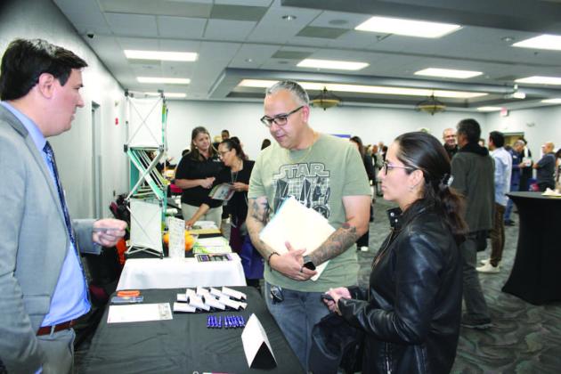 Showcase attendees confer with representatives from the U.S. Dept. of Commerce and CareerSource Central Florida. PHOTO/TERRY LLOYD