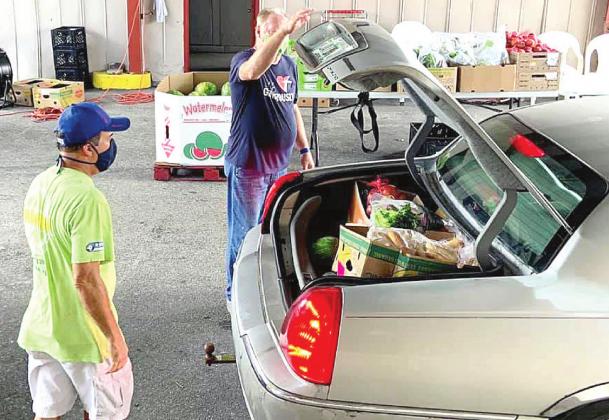 Two of the St. Cloud Community Food Pantry’s 250 volunteers fills a client’s trunk with food during a recent drive through distribution. The organization was one of several local pantries to receive financial assistance from disaster relief organization. SUBMITTED PHOTO