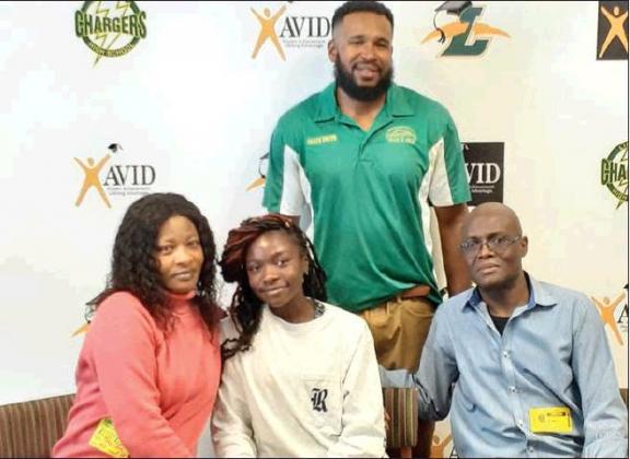 news-gazette photo/J. Daniel pearson Surrounded by her parents and Liberty Head Coach Alfonza Smith (back row), Christelle Bonzil (front center) signs her letter of intent to run track at Rice University.