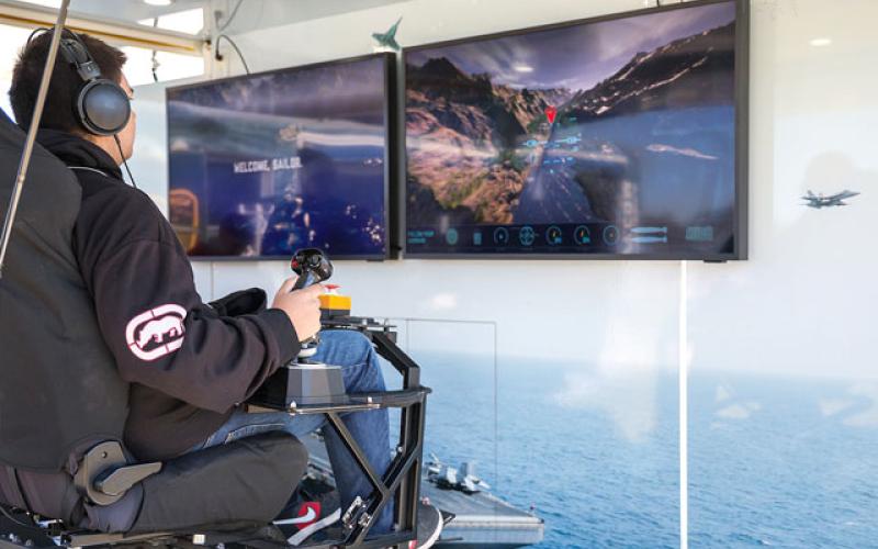Tohopekaliga High students try their hands at landing a fighter jet on aircraft carrier on the “Fly” Experience and other virtual reality missions at last week’s U.S. Navy Strike Group Experience tour. (Photo/Taylor McFee)