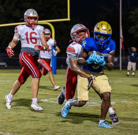 Lake Mary defenders Nazir McMillan (8) and Patrick Ryan (16) try to bring down Osceola's Jeff Sinophat in Friday's 17-12 Kowboys loss. (Photo/Dan Pearson)