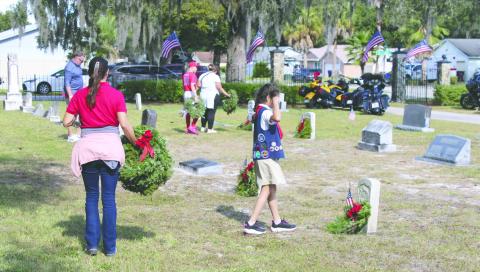 A young volunteer places a wreath on a Civil War veteran’s grave at Mt. Peace Cemetery Saturday (Photo/Terry Lloyd).